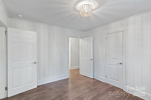 2953 Enfield Rd, Charlotte, NC 28205 - unfurnished bedroom with dark wood-style flooring, a chandelier, a textured ceiling, baseboards, and ornamental molding