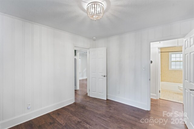 2953 Enfield Rd, Charlotte, NC 28205 - unfurnished bedroom with dark wood finished floors, a chandelier, baseboards, crown molding, and a textured ceiling