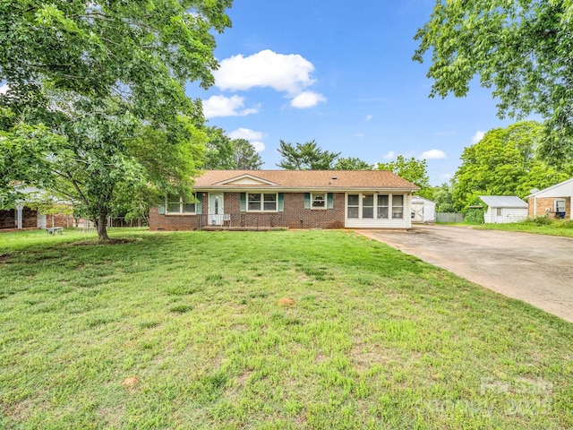 ranch-style home featuring driveway, brick siding, and a front yard