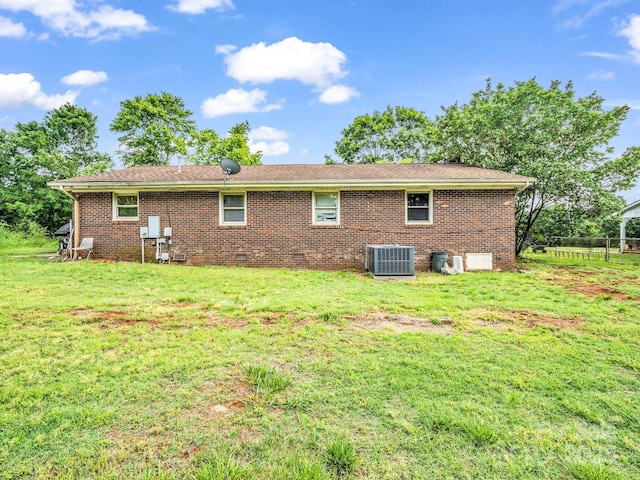 back of house with central AC, crawl space, a lawn, and brick siding