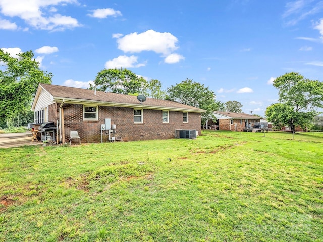 back of house with a lawn, brick siding, central AC, and crawl space