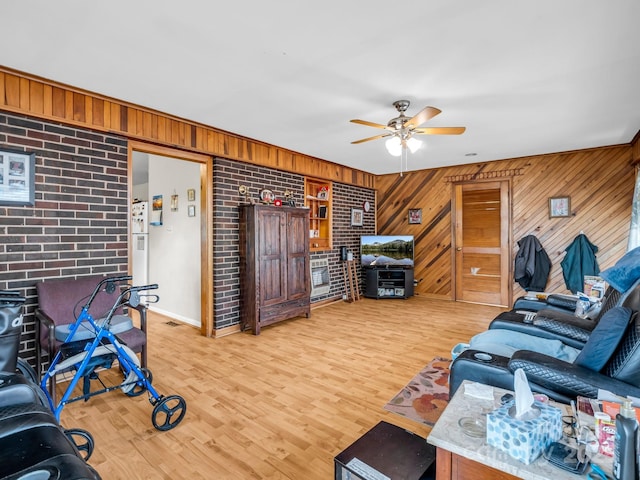 living room with ceiling fan, wood walls, wood finished floors, and baseboards