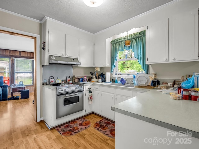 kitchen with under cabinet range hood, stainless steel range with electric cooktop, light wood finished floors, a sink, and white cabinetry