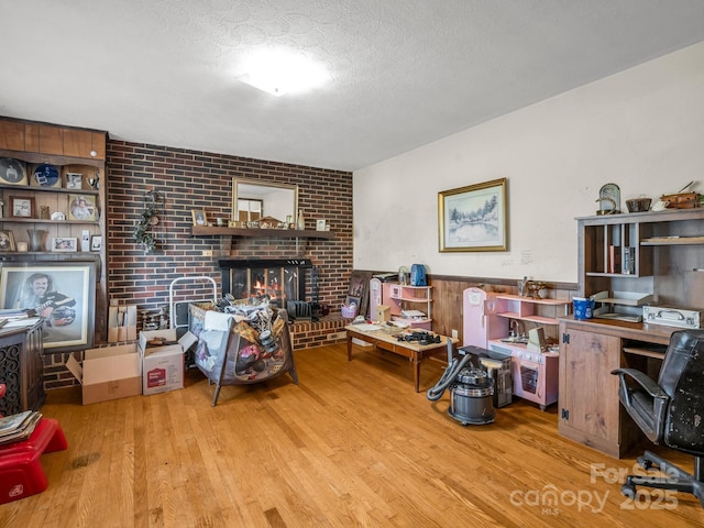 office area featuring wood finished floors, a fireplace, a textured ceiling, and a wainscoted wall