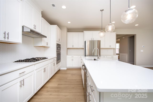 256 W Waterlynn Rd, Mooresville, NC 28117 - kitchen with under cabinet range hood, stainless steel appliances, a sink, an island with sink, and light countertops