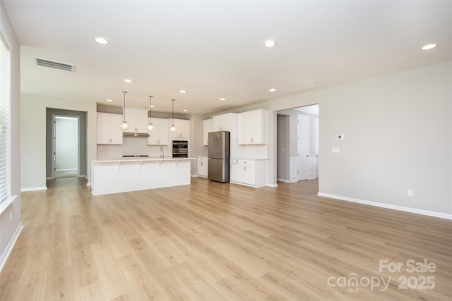 256 W Waterlynn Rd, Mooresville, NC 28117 - unfurnished living room featuring light wood finished floors, recessed lighting, baseboards, and a sink