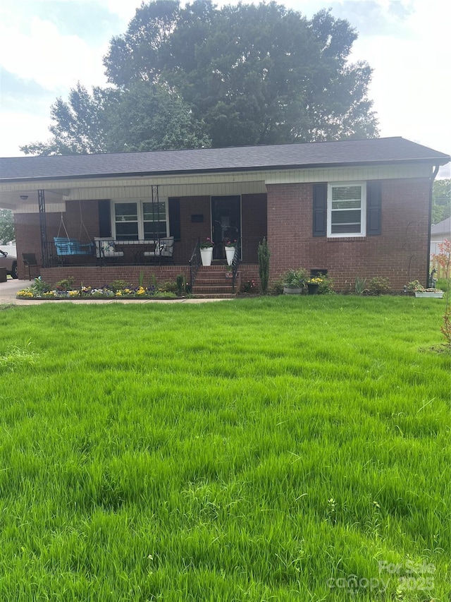ranch-style home featuring a front lawn, covered porch, and brick siding