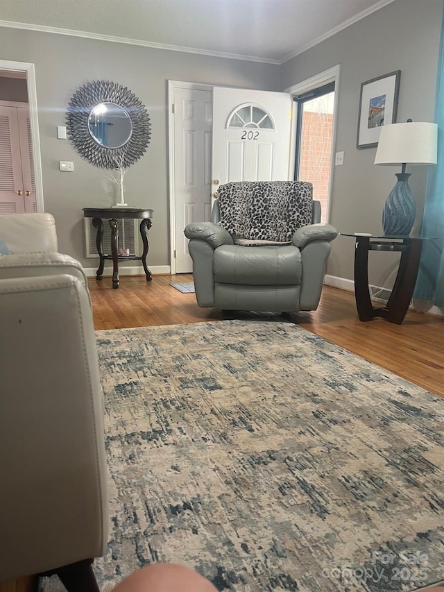 living area with ornamental molding, wood finished floors, and baseboards