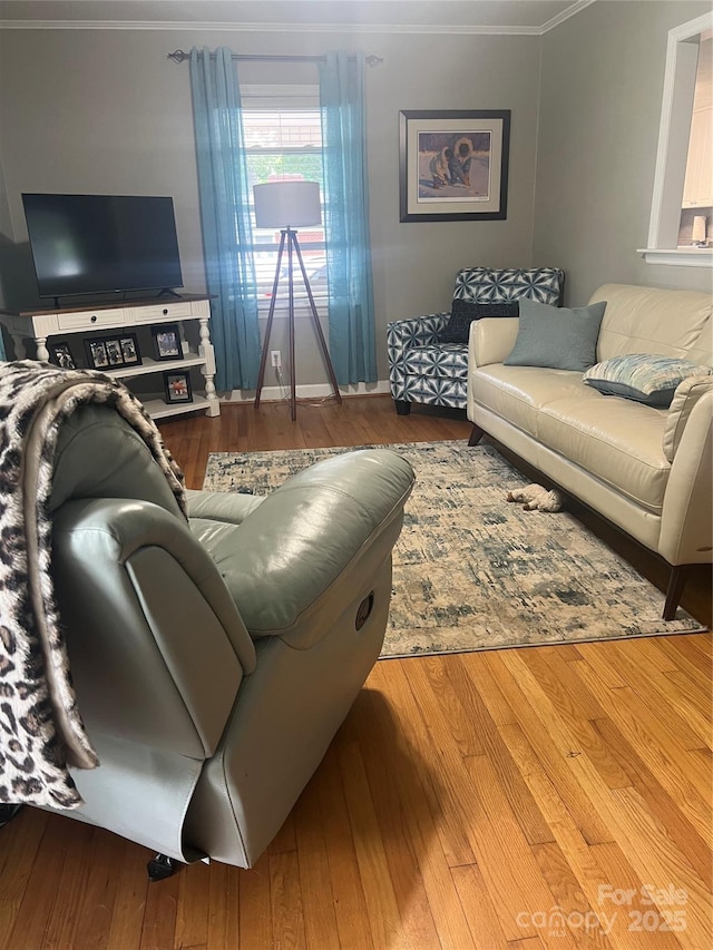 living area with ornamental molding, wood finished floors, and baseboards