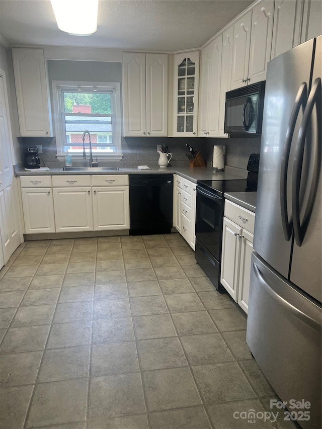 kitchen with black appliances, a sink, and white cabinetry
