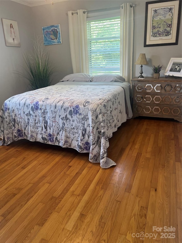 bedroom with wood finished floors and crown molding