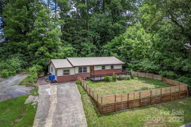 single story home featuring driveway, a deck, metal roof, and a view of trees