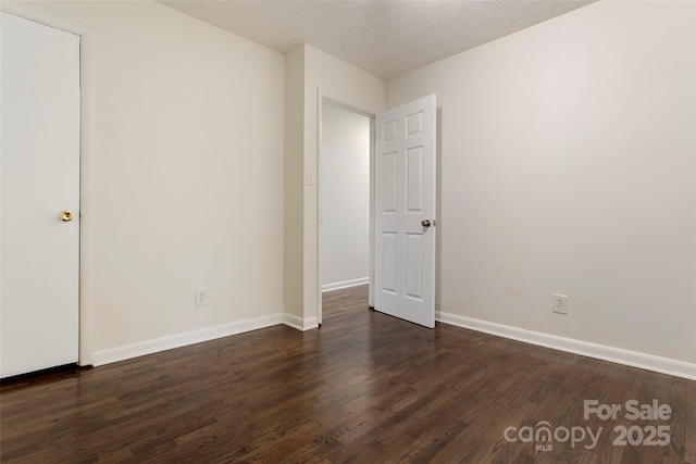 unfurnished room with dark wood-style floors, baseboards, and a textured ceiling