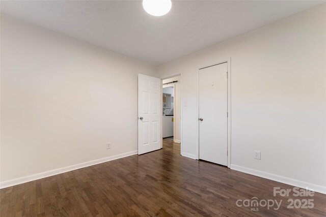 unfurnished bedroom with baseboards and dark wood-type flooring
