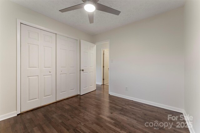 unfurnished bedroom with dark wood-style flooring, baseboards, a closet, a textured ceiling, and a ceiling fan