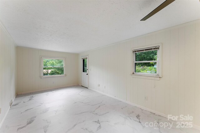 unfurnished room with a textured ceiling and baseboards