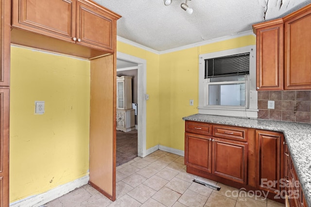 kitchen featuring tasteful backsplash, baseboards, light tile patterned flooring, ornamental molding, and brown cabinetry