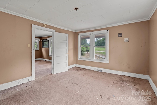 carpeted spare room featuring ornamental molding, plenty of natural light, baseboards, and a pendent fire sprinkler