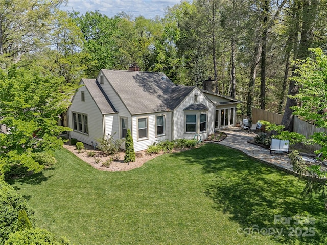 view of front of house featuring a chimney, a patio, and roof with shingles