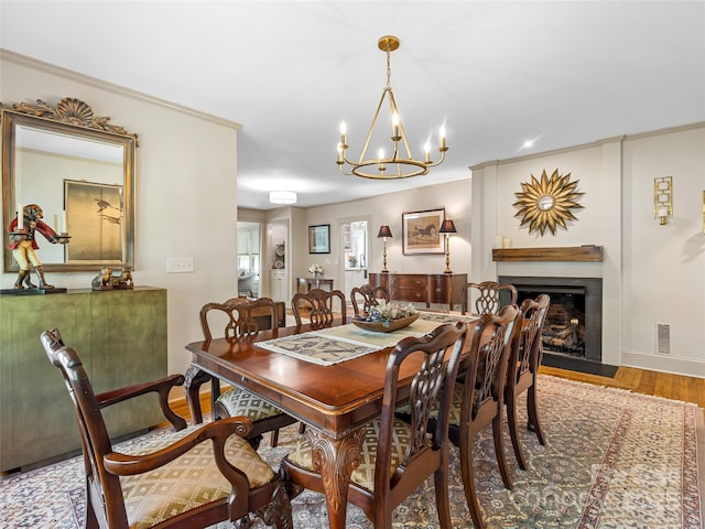 dining area with a chandelier, wood finished floors, a fireplace with flush hearth, and baseboards