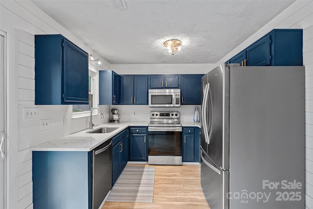8007 Maxwelton Dr, Huntersville, NC 28078 - kitchen featuring appliances with stainless steel finishes, blue cabinets, a sink, a textured ceiling, and light wood-style flooring