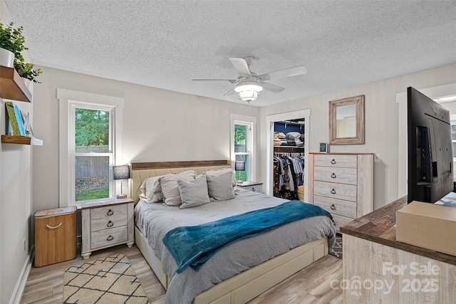 8007 Maxwelton Dr, Huntersville, NC 28078 - bedroom with light wood-style floors, multiple windows, a textured ceiling, a closet, and a walk in closet