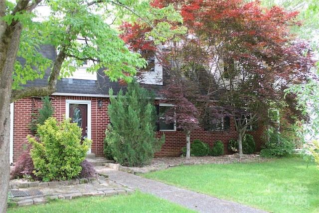 426/432 Maple St, Brevard, NC 28712 - view of property hidden behind natural elements featuring a front lawn, a shingled roof, and brick siding