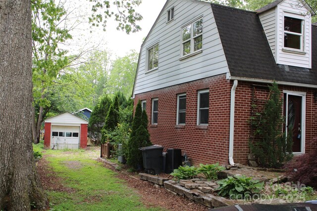 426/432 Maple St, Brevard, NC 28712 - view of property exterior with brick siding, a gambrel roof, a detached garage, an outbuilding, and roof with shingles