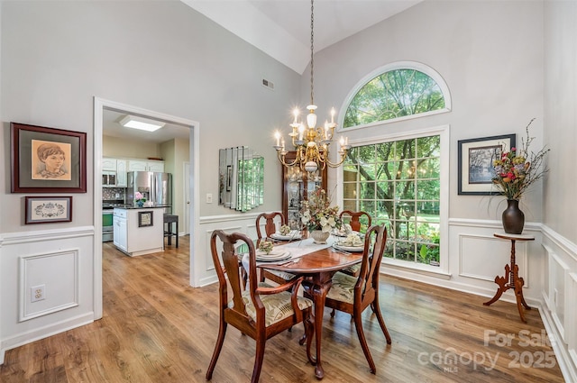 5208 Black Oak Ln, Waxhaw, NC 28173 - dining space featuring a chandelier, a decorative wall, light wood-style floors, plenty of natural light, and wainscoting