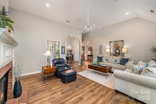 5208 Black Oak Ln, Waxhaw, NC 28173 - living area with arched walkways, a brick fireplace, light wood finished floors, recessed lighting, and a ceiling fan