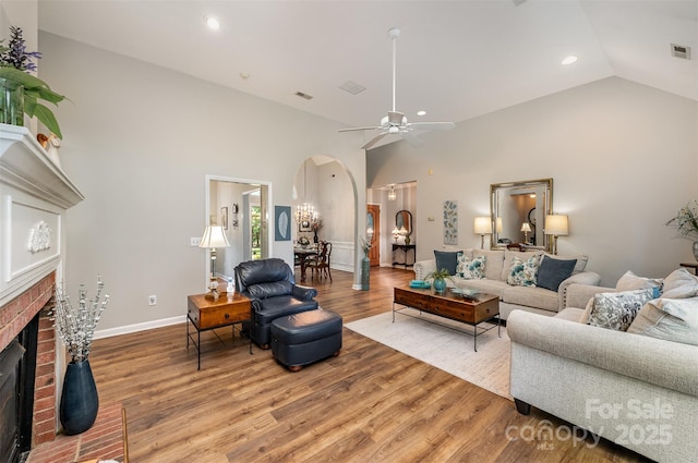 5208 Black Oak Ln, Waxhaw, NC 28173 - living area with arched walkways, a brick fireplace, light wood-style flooring, recessed lighting, and a ceiling fan