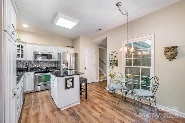 5208 Black Oak Ln, Waxhaw, NC 28173 - kitchen featuring appliances with stainless steel finishes, dark countertops, a breakfast bar, white cabinets, and a chandelier