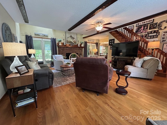 2815 Penny Park Dr, Gastonia, NC 28052 - living area featuring wood finished floors, a textured ceiling, a brick fireplace, beamed ceiling, and a ceiling fan