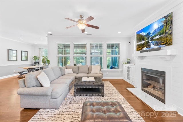3918 Halcyon Dr, Huntersville, NC 28078 - living room with ornamental molding, ceiling fan, a glass covered fireplace, wood finished floors, and baseboards