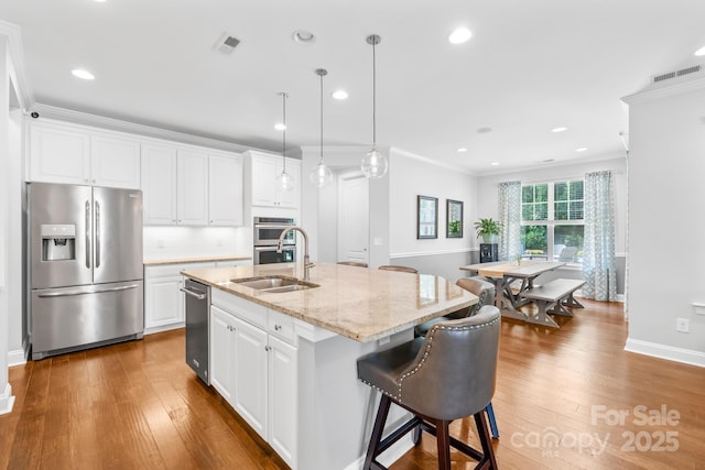 3918 Halcyon Dr, Huntersville, NC 28078 - kitchen featuring stainless steel appliances, a sink, a center island with sink, wood finished floors, and crown molding