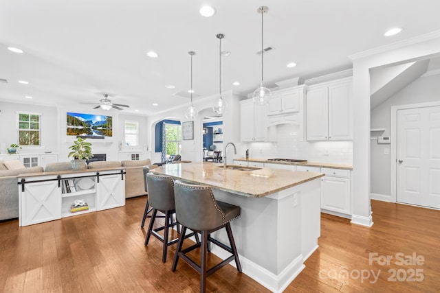 3918 Halcyon Dr, Huntersville, NC 28078 - kitchen featuring a sink, arched walkways, open floor plan, stainless steel gas stovetop, and white cabinetry