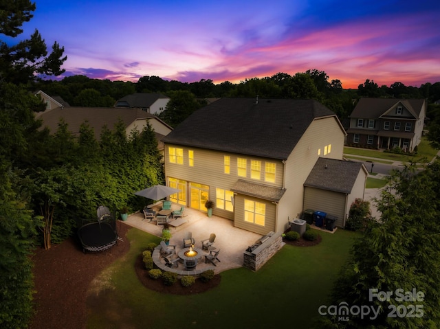 3918 Halcyon Dr, Huntersville, NC 28078 - back of house at dusk with a patio, a yard, an outdoor living space with a fire pit, cooling unit, and driveway
