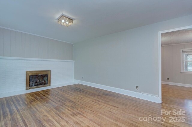 3951 Whitehall Dr, Charlotte, NC 28208 - unfurnished living room with wood finished floors, a fireplace, baseboards, wood walls, and crown molding