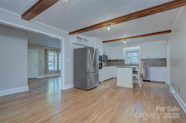 3951 Whitehall Dr, Charlotte, NC 28208 - kitchen with stainless steel appliances, beam ceiling, tasteful backsplash, light wood-style flooring, and white cabinets