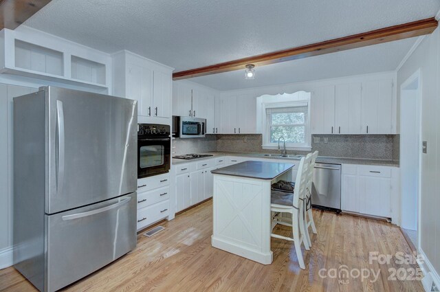3951 Whitehall Dr, Charlotte, NC 28208 - kitchen with black appliances, a sink, decorative backsplash, light wood-style flooring, and a textured ceiling