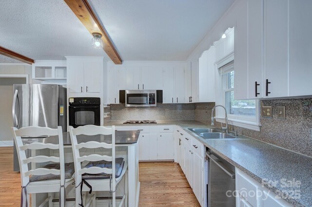 3951 Whitehall Dr, Charlotte, NC 28208 - kitchen with stainless steel appliances, a sink, beamed ceiling, white cabinetry, and light wood-style flooring