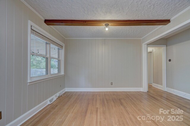 3951 Whitehall Dr, Charlotte, NC 28208 - spare room with a textured ceiling, light wood-style flooring, beamed ceiling, baseboards, and wooden walls