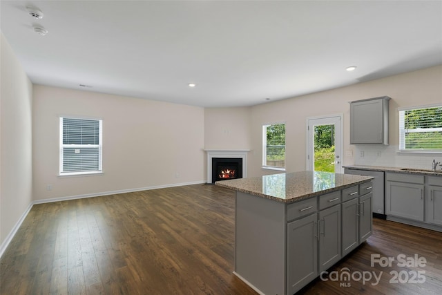 383 Ridgeview Ln, Mars Hill, NC 28754 - kitchen featuring gray cabinets, a kitchen island, dark wood-style flooring, light stone countertops, and a lit fireplace