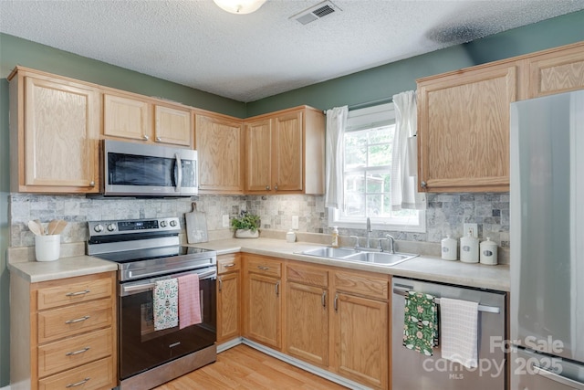 2023 E Park Dr, Lancaster, SC 29720 - kitchen with appliances with stainless steel finishes, a sink, light brown cabinetry, light countertops, and a textured ceiling
