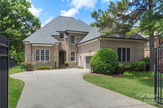 6132 Sharon Rd, Charlotte, NC 28210 - french provincial home featuring an attached garage, concrete driveway, brick siding, and a shingled roof