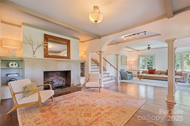 66 Fox Trot Ln, Tryon, NC 28782 - living area with decorative columns, arched walkways, a brick fireplace, wood finished floors, and stairs