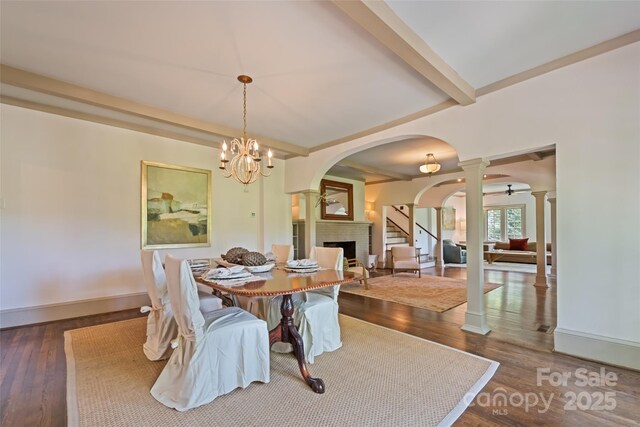66 Fox Trot Ln, Tryon, NC 28782 - dining space featuring ornate columns, arched walkways, a fireplace, wood finished floors, and beam ceiling