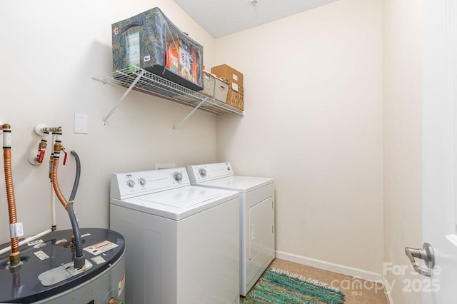 laundry room featuring washer and clothes dryer, water heater, light tile patterned floors, and baseboards