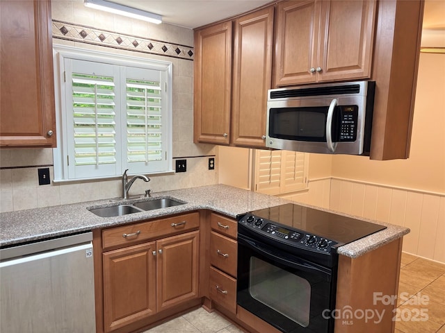 7212 Bradley Ct, Charlotte, NC 28227 - kitchen featuring appliances with stainless steel finishes, a sink, light tile patterned floors, tasteful backsplash, and a wainscoted wall