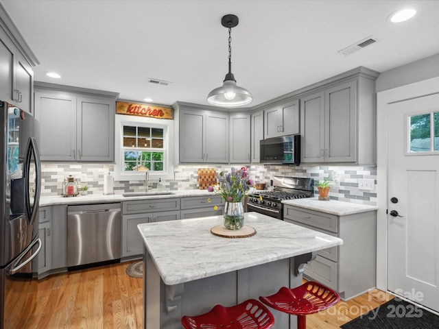 107 Pressley St, Clover, SC 29710 - kitchen with stainless steel appliances, a sink, gray cabinetry, decorative backsplash, and pendant lighting